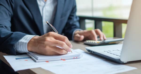 accountant working on laptop and paper with pen